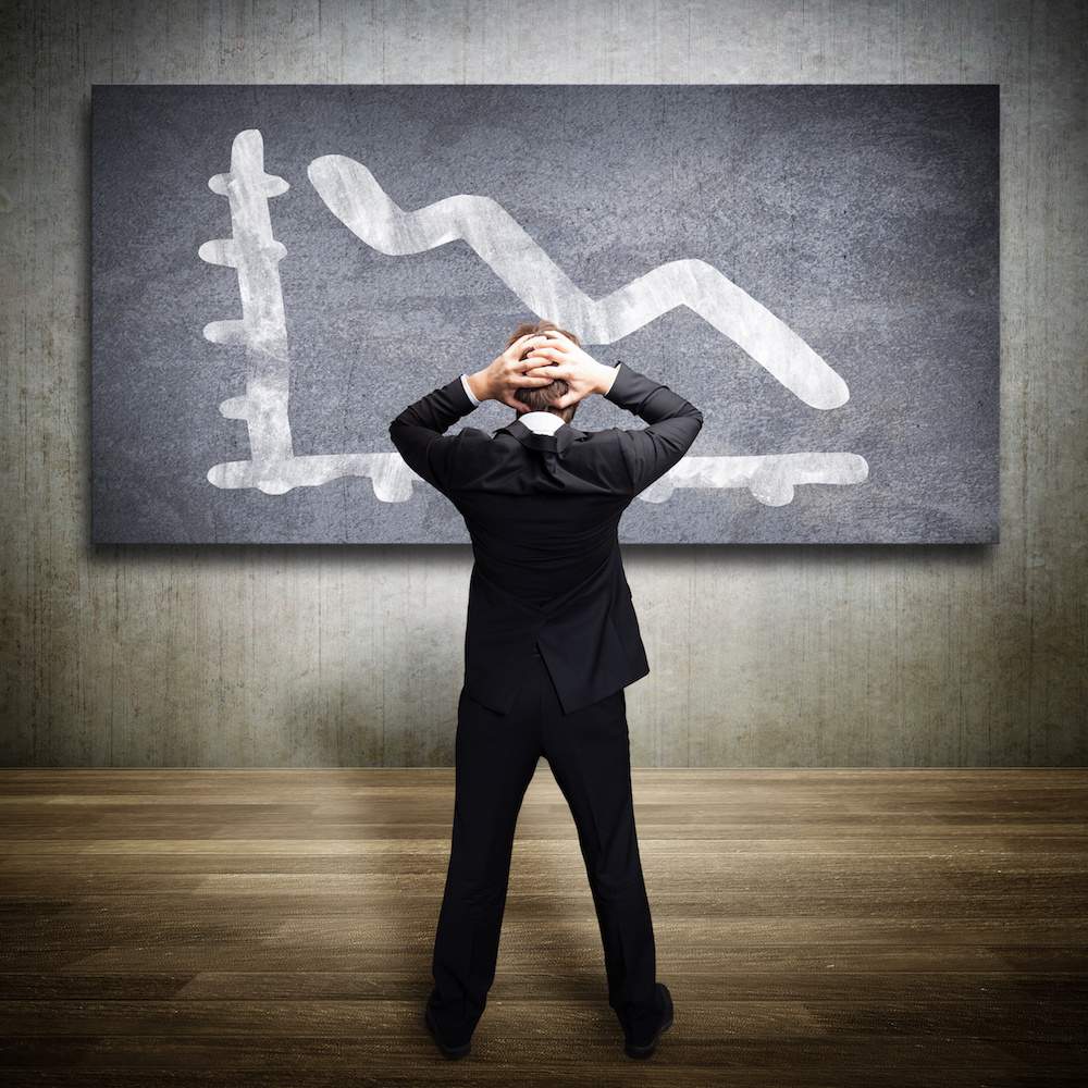 Exasperated man looking at a trending downward graph